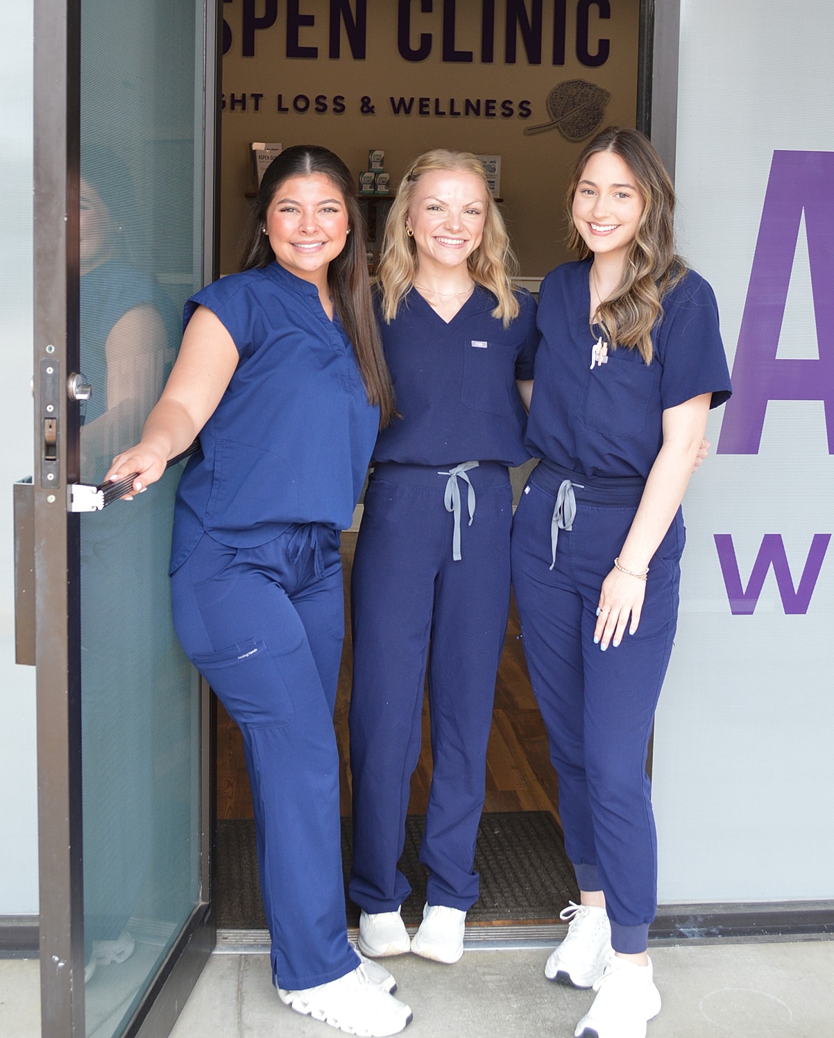 Three healthcare professionals at clinic entrance.
