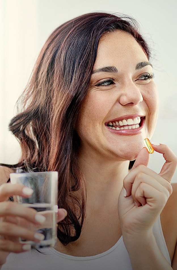 Woman smiling with a vitamin and water.