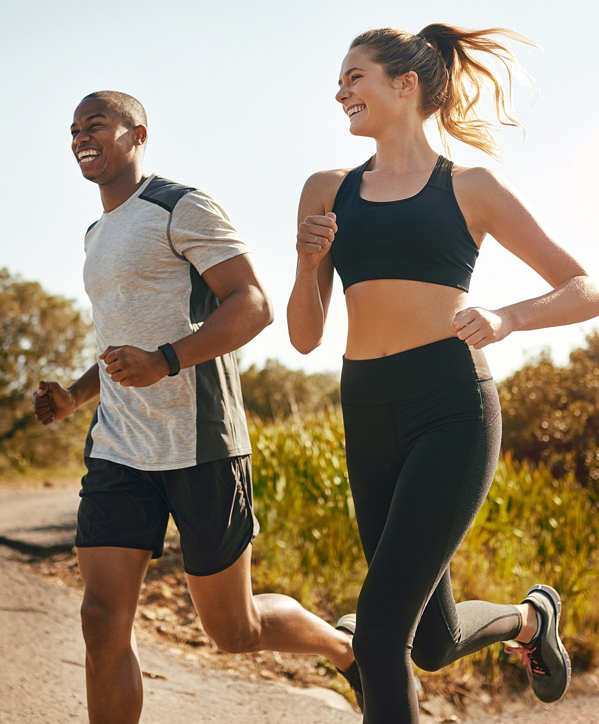 Couple jogging together in sunny outdoor setting.