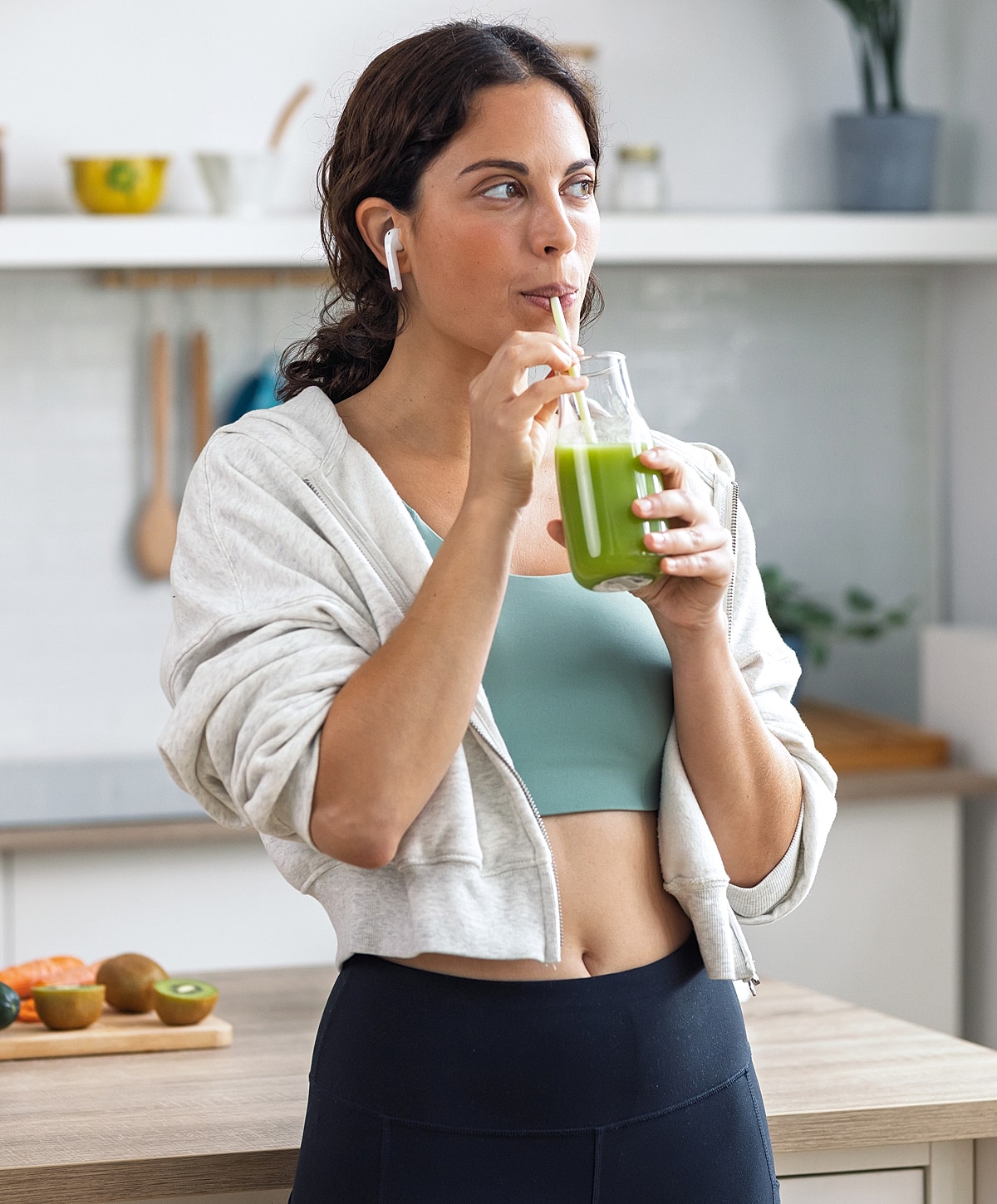 Woman enjoying a green smoothie in the kitchen.