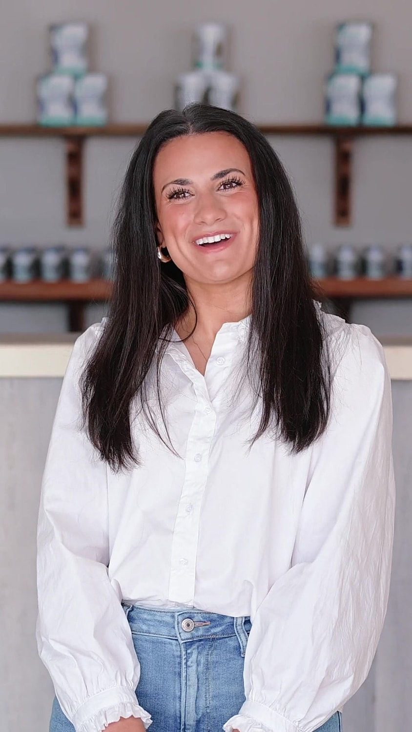 Smiling woman in casual white blouse and jeans.